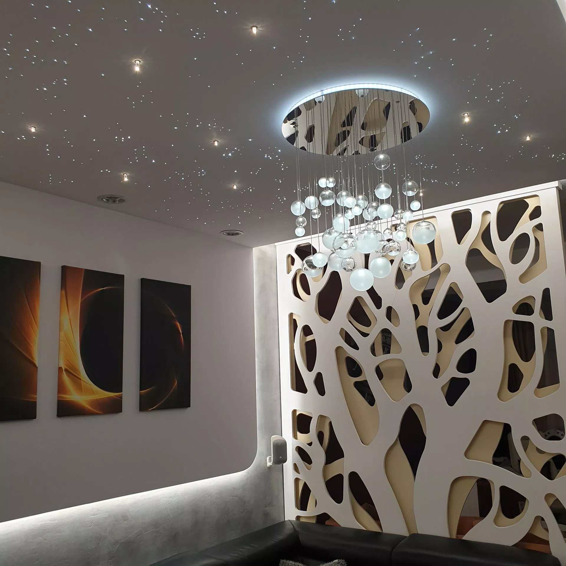 Tiny circular LED chandelier with starry sky effects arround it.